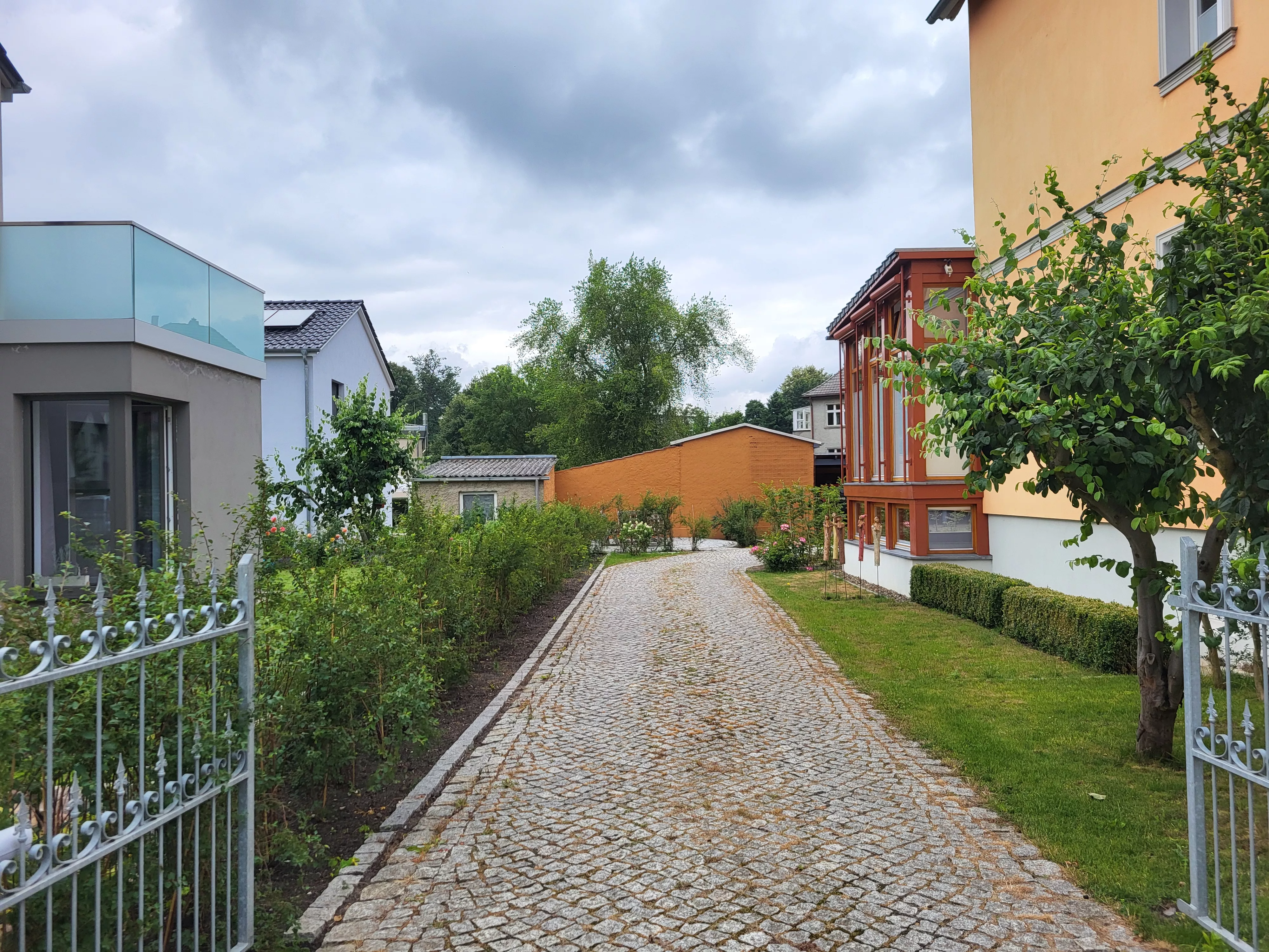 Gepflasterter Gartenweg mit Rosenbeeten entlang der Stadtvilla von ZeitWohnen in Neubrandenburg – gepflegte Außenanlage für betreutes Wohnen